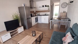 Un salon moderne avec un téléviseur, une table basse en bois et un canapé.