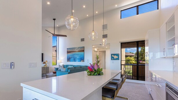 Una cocina moderna con una isla central, iluminación colgante y vistas al exterior.