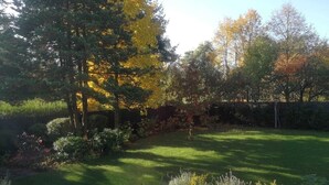 A well-maintained garden with a variety of trees and shrubs, a neatly trimmed lawn, and a white planter box with plants. - Family Oasis 20min from Warsaw (Piaseczno)
