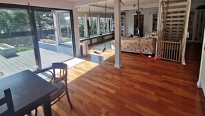 A spacious living area with a wooden floor, large sliding glass doors leading to a deck, a sofa set, and a swing chair. - Family Oasis 20min from Warsaw (Piaseczno)