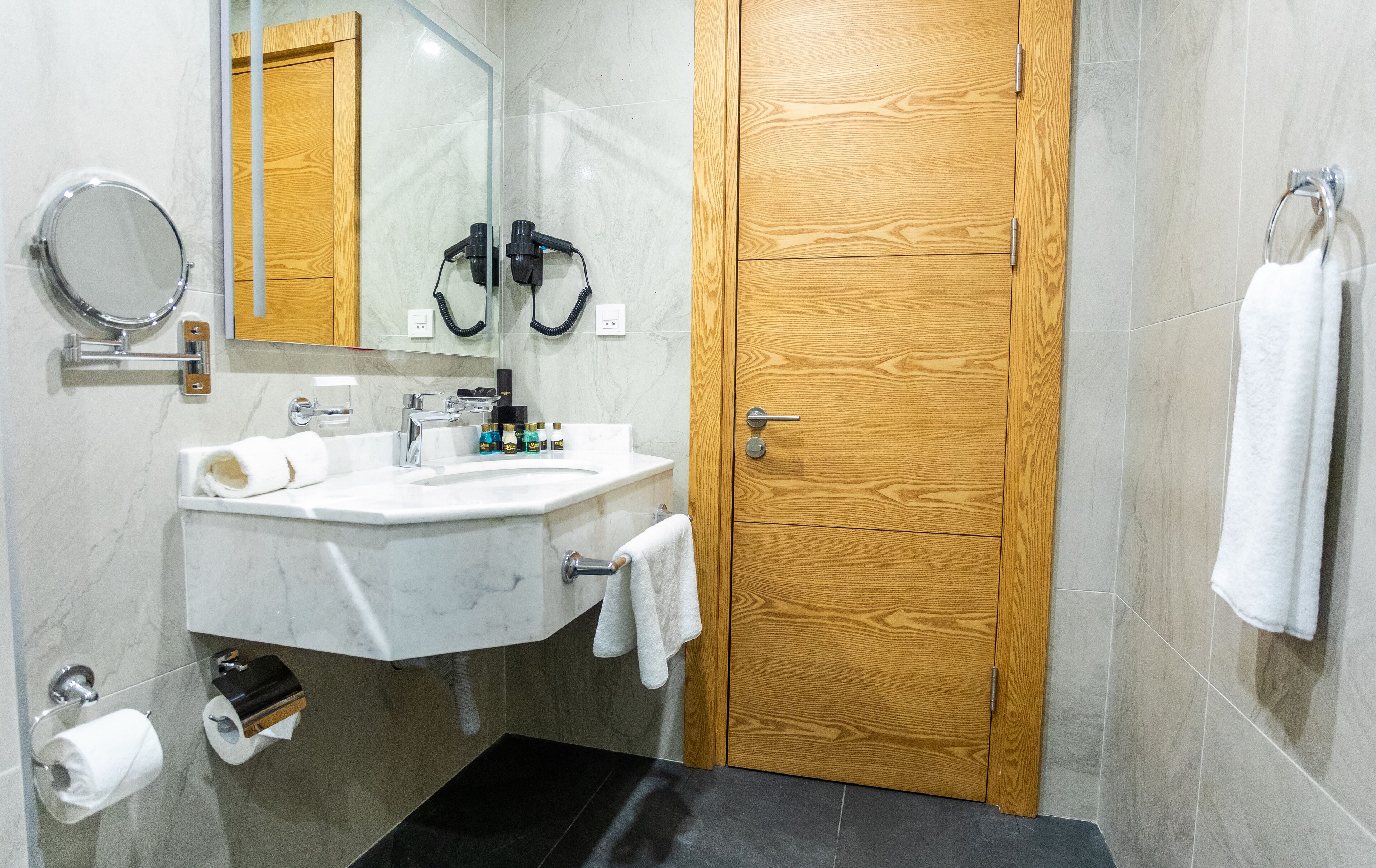 A bathroom with a wooden door, a sink with a mirror, and a towel rack.