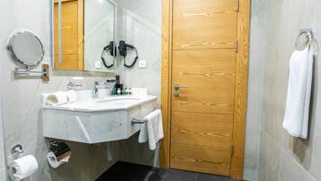 A bathroom with a wooden door, a sink with a mirror, and a towel rack.