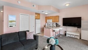 A compact living space with a kitchenette, a sofa, a TV, and a small dining area.