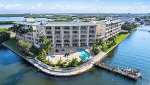 A multi-story hotel with a pool, located near a body of water.