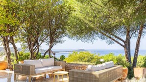 An outdoor seating area with wicker furniture and a stone wall, overlooking a coastal landscape. - VILLA CAMELIA- 5 bedrooms, sea view, swimming pool (ALBITRECCIA)