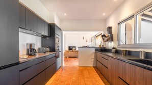 A modern kitchen with dark cabinetry, a central island, and a tiled floor. - VILLA CAMELIA- 5 bedrooms, sea view, swimming pool (ALBITRECCIA)