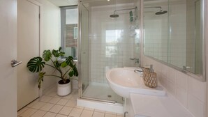 A modern bathroom with a glass-enclosed shower, a white sink, and a potted plant. - Beautiful 1-bed in St Kilda w/ Parking & Terrace (St Kilda)