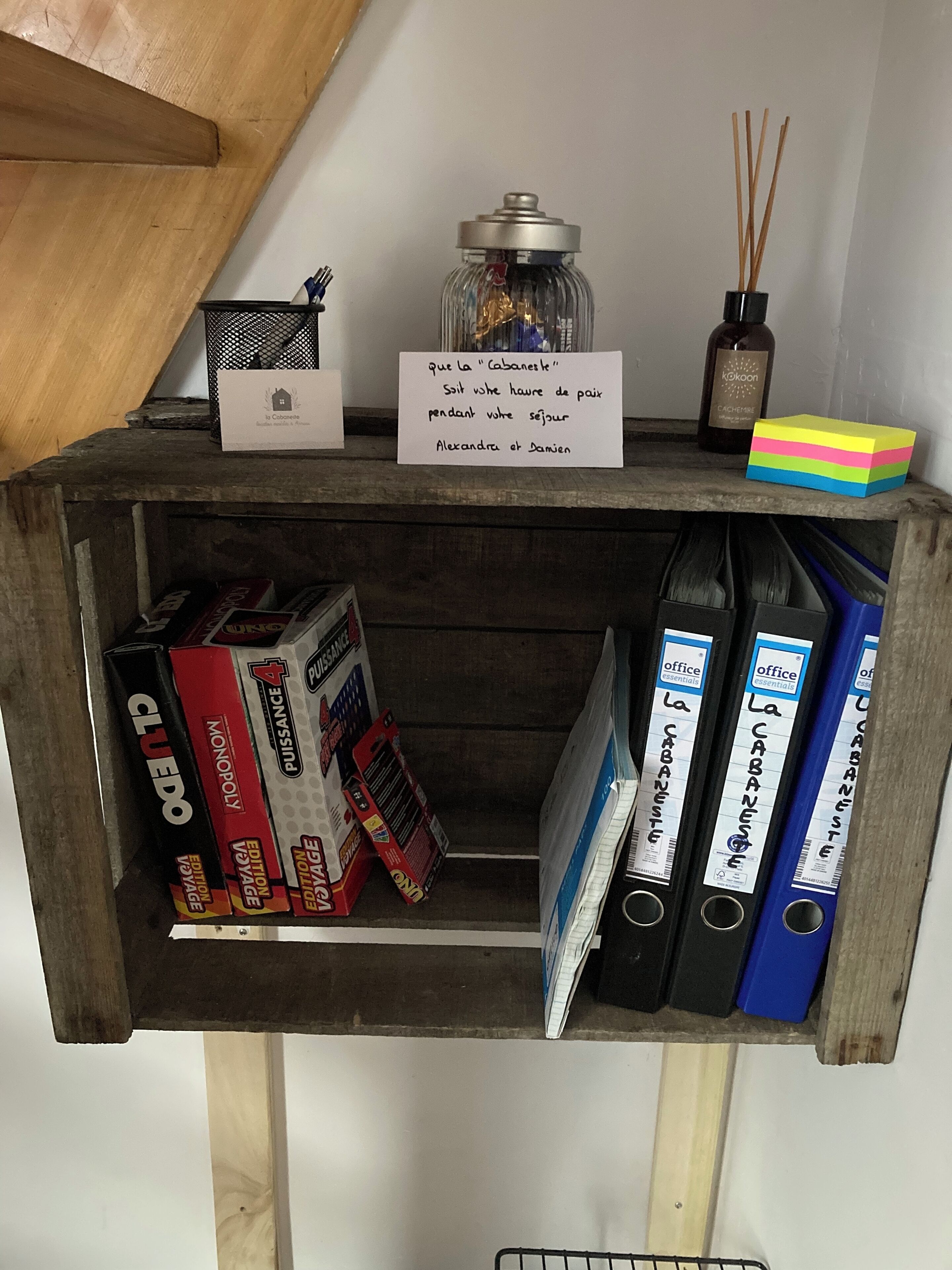 Une étagère en bois avec une pancarte, des livres et un chandelier.