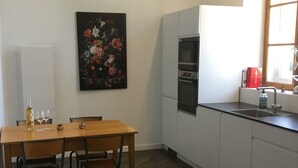 Una cocina moderna con armarios blancos, una mesa de comedor de madera y un suelo con patrón de espiga.