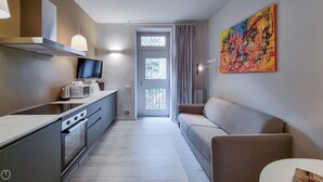 Eine moderne Küche mit Flachbildfernseher, Mikrowelle und Herd. Es gibt ein Sofa und ein Bild an der Wand.
