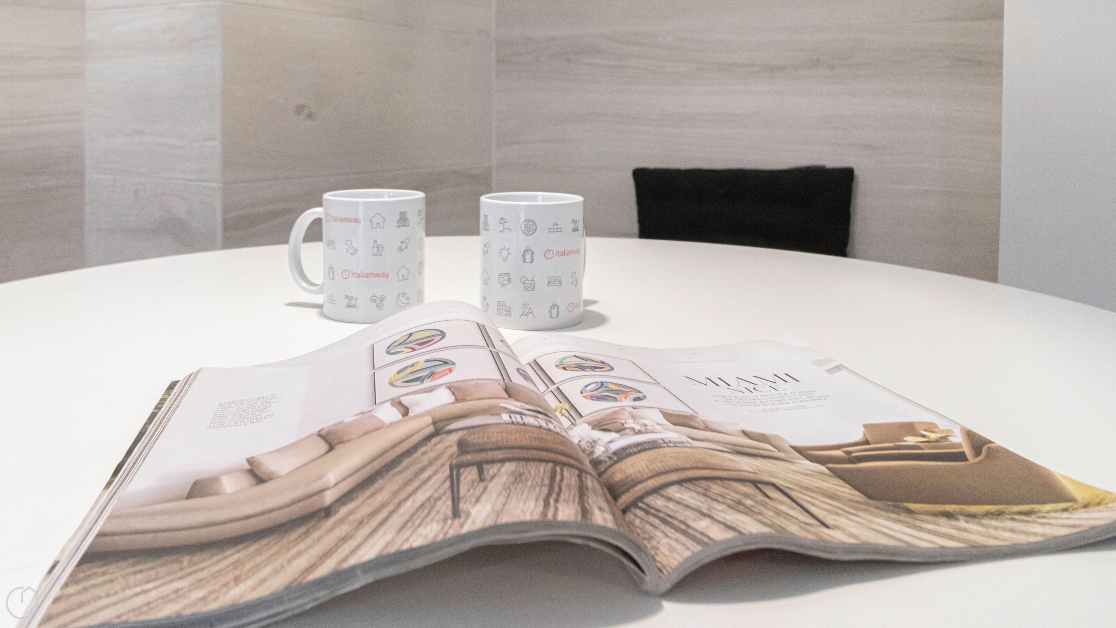 A magazine spread on a table with two coffee mugs and a chair in the background.