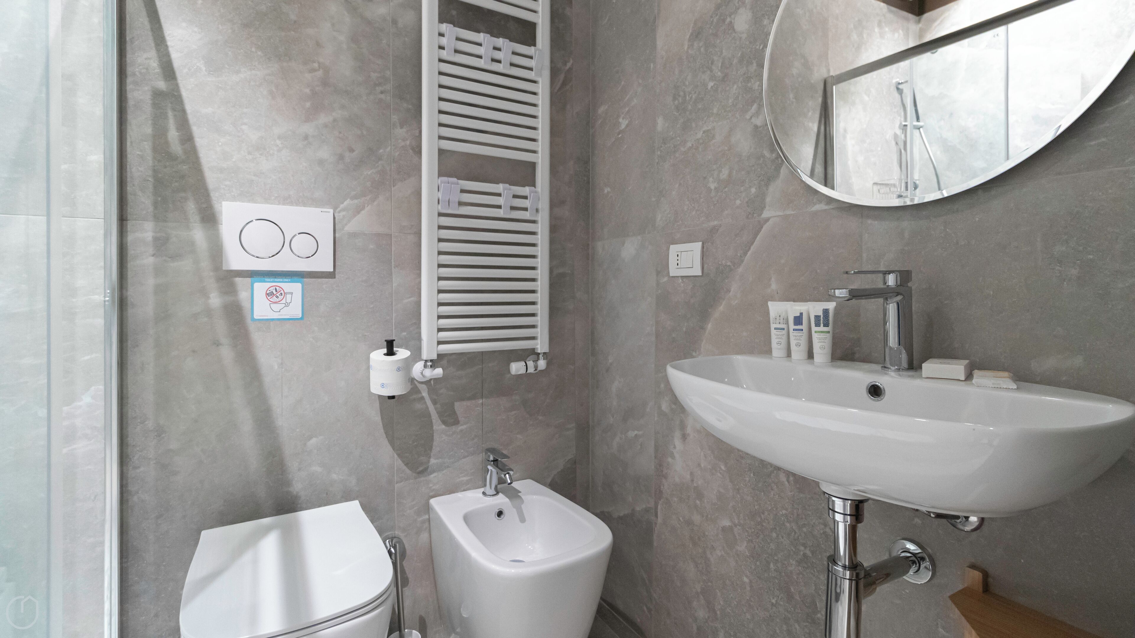 Ein modernes Badezimmer mit Toilette, Bidet, Waschbecken und Spiegel.