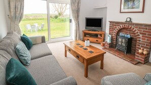 A living room with a sofa, a coffee table, a TV, and a fireplace. - Dolafon (Pwllheli)