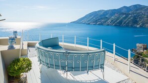 A terrace with a round table and chairs, overlooking a coastal sea and mountains. - Luxury Villa Vittoria- Villa With Garden Swimming Pool and Jacuzzi Overlooking the sea (Maiori)