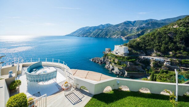 A coastal property with a circular outdoor seating area, a pool, and a view of the sea and mountains. - Luxury Villa Vittoria- Villa With Garden Swimming Pool and Jacuzzi Overlooking the sea (Maiori)