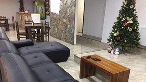 Una sala de estar con un sofá modular, una mesa de centro de madera y un árbol de Navidad.