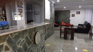 Un vestíbulo con mostrador de piedra, una zona de comedor con mesa y sillas, y un sofá.
