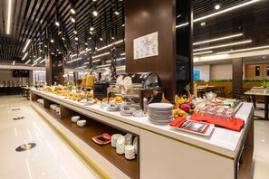 A buffet setup with various food items and utensils, a sign indicating 'Supper', and a modern ceiling design. - Horison Diana Timika (Timika)