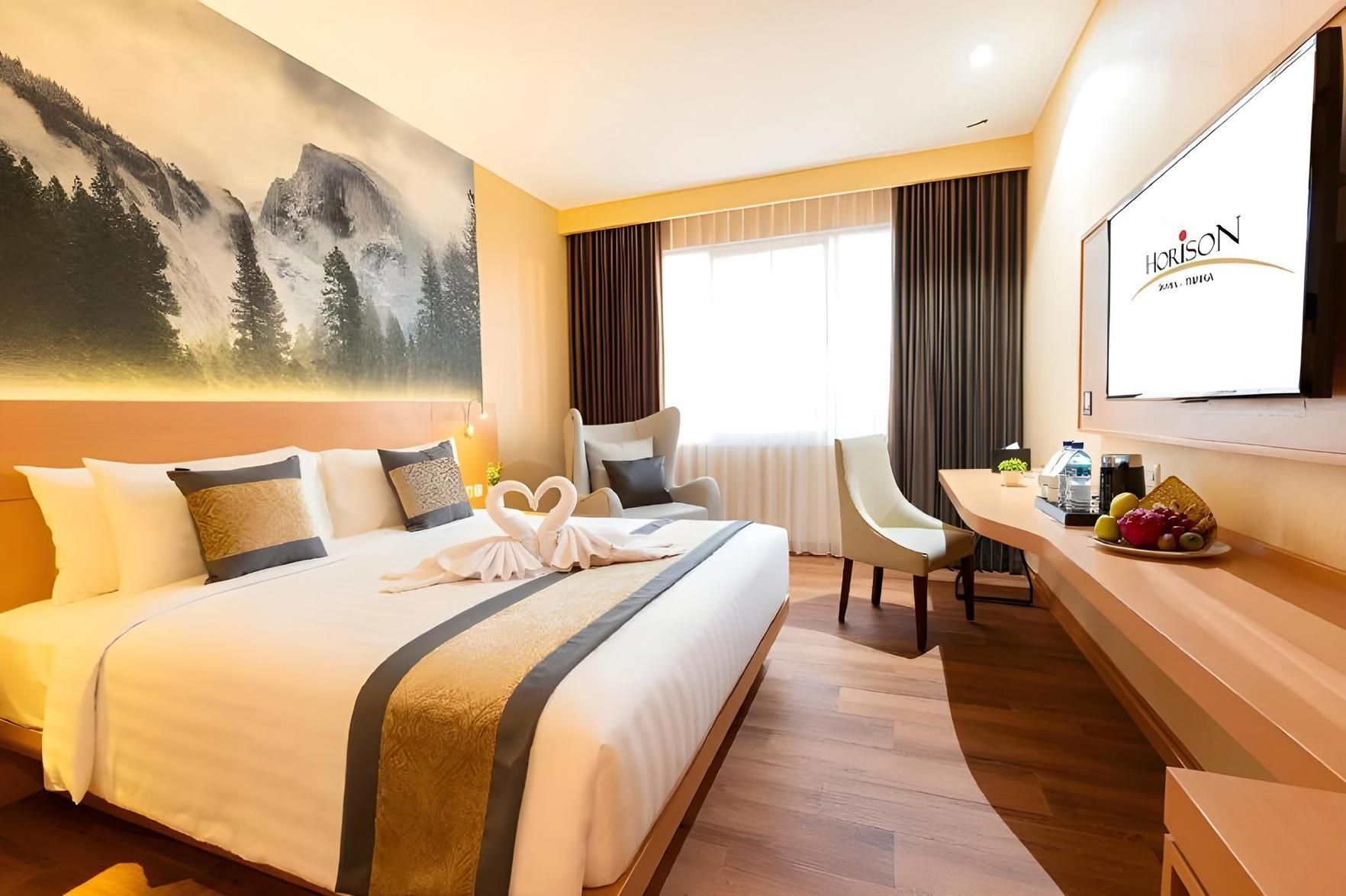 Una habitación de hotel con una cama grande, un escritorio, una silla, un televisor y un cuadro en la pared.