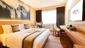 Una habitación de hotel con una cama grande, un escritorio, una silla, un televisor y un cuadro en la pared.