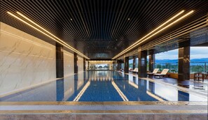 Una piscina interior moderna con suelo reflectante, ventanas amplias y vistas a las montañas.