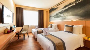 A hotel room with two beds, a desk with a chair, a TV, and a painting of a landscape.