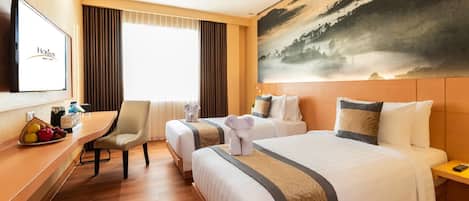 Habitación de hotel con dos camas, un escritorio con silla, un televisor y un cuadro de un paisaje.