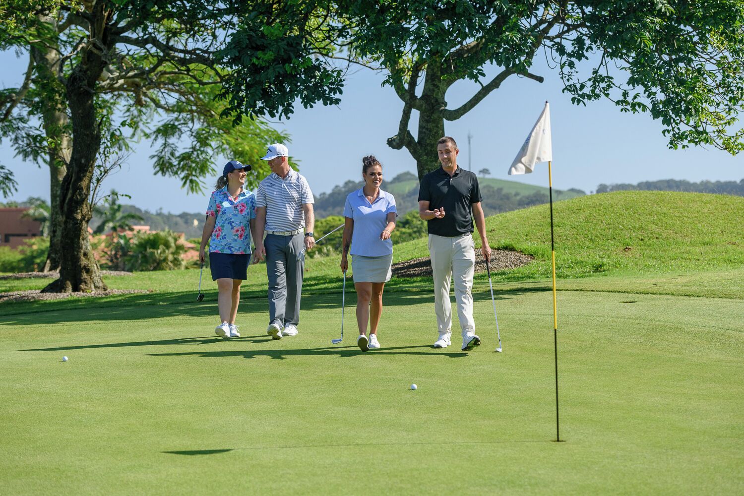 Un camp de golf amb quatre persones a prop d'una banderola.