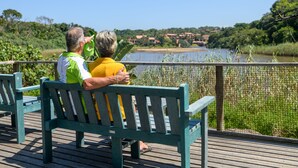 A wooden deck with benches overlooking a river and a distant village.
