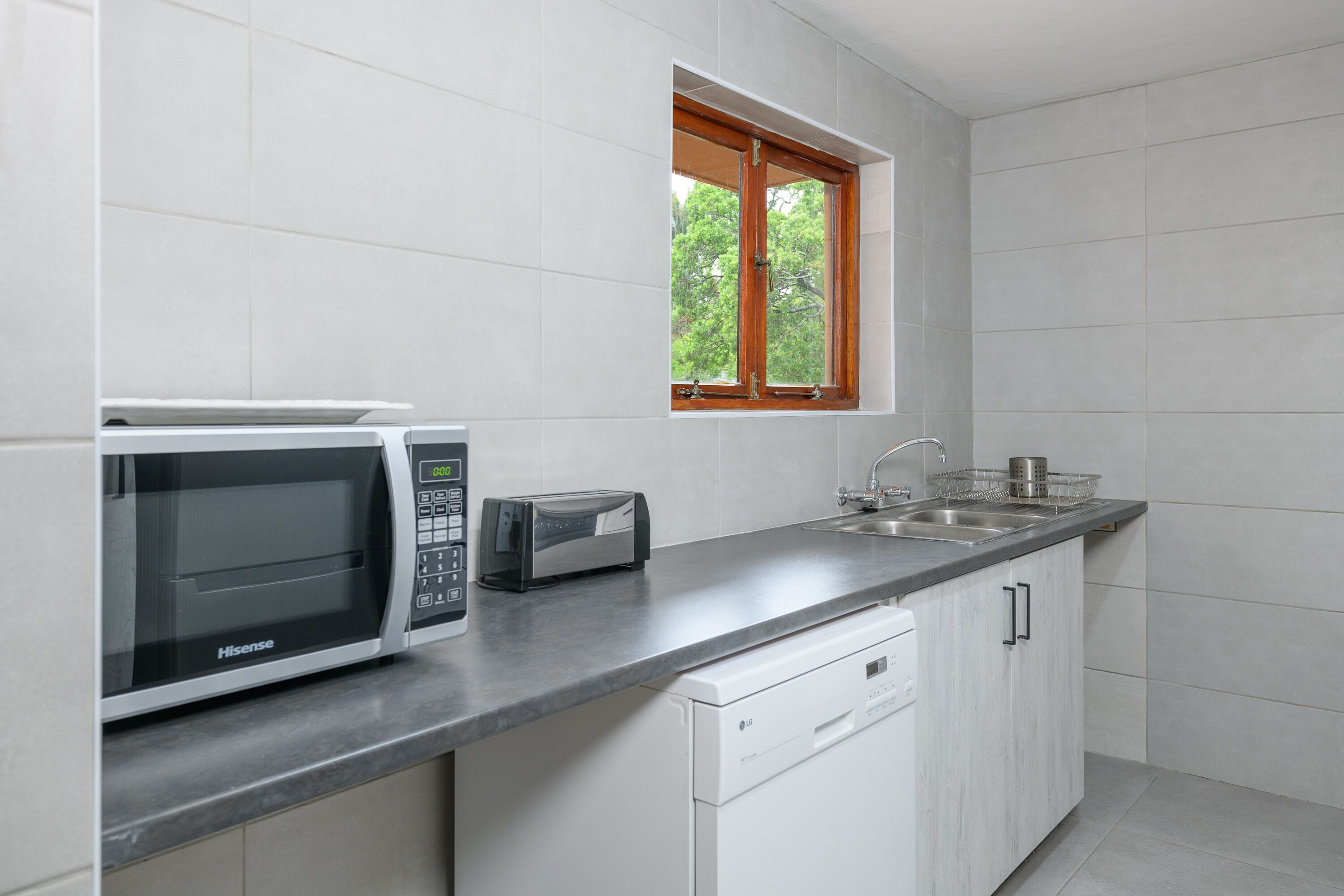 A modern kitchen with a microwave, toaster, sink, and dishwasher.