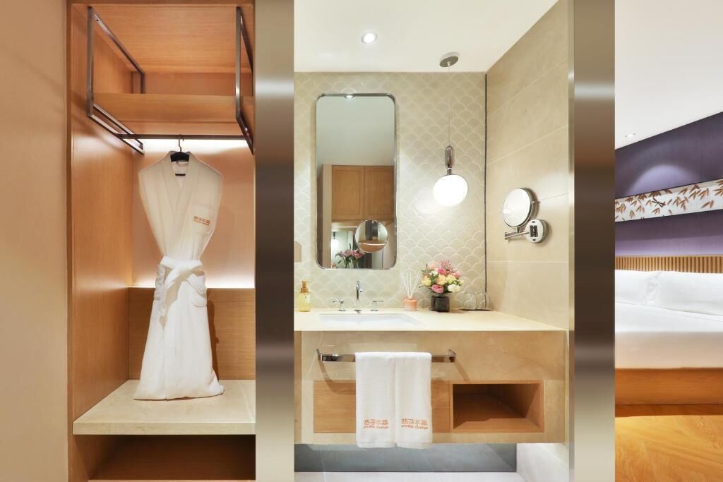 A hotel room with a wooden vanity, a mirror, a sink, and a bed.