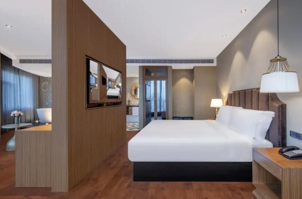 Een hotelkamer met een bed, een bureau, een stoel, een televisie en een lamp.
