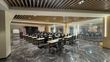A conference room with a long table, chairs, a whiteboard, and a projector screen.