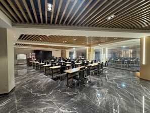 Una sala de conferencias con una larga mesa, sillas, una pizarra y una pantalla de proyector.