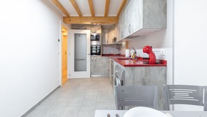 Une cuisine moderne avec des poutres en bois, un plan de travail rouge et des appareils électroménagers en acier inoxydable.