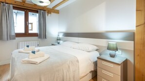 Une chambre à coucher avec un lit, des tables de chevet, une lampe et une fenêtre avec des rideaux.