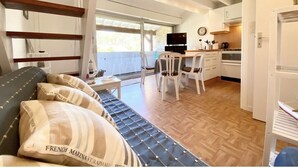A compact living space with a sofa, a dining table, and a kitchen area. - Les Pins Residence: Duplex with a beachfront terrace—just a stone's throw away and in a fantastic location (Carnac)