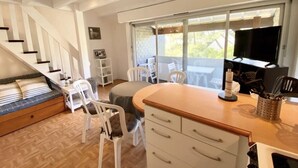 A compact living space with a built-in bed, a dining area with a table and chairs, a kitchen counter, and a large window offering a view of the outdoors. - Les Pins Residence: Duplex with a beachfront terrace—just a stone's throw away and in a fantastic location (Carnac)