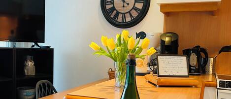 A kitchen with a wooden countertop, a bottle of wine, a bowl, a clock, and a coffee maker.