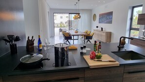 A modern kitchen with a central island, built-in appliances, and a dining area with a view. - CASA NIDO - Modern, very spacious villa with heated pool (Lajares)