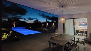 A modern outdoor dining area with a pool, a dining table, and chairs. - CASA NIDO - Modern, very spacious villa with heated pool (Lajares)