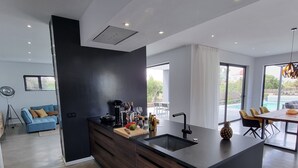 A modern kitchen with a dark island, wooden cabinets, and a large window. - CASA NIDO - Modern, very spacious villa with heated pool (Lajares)