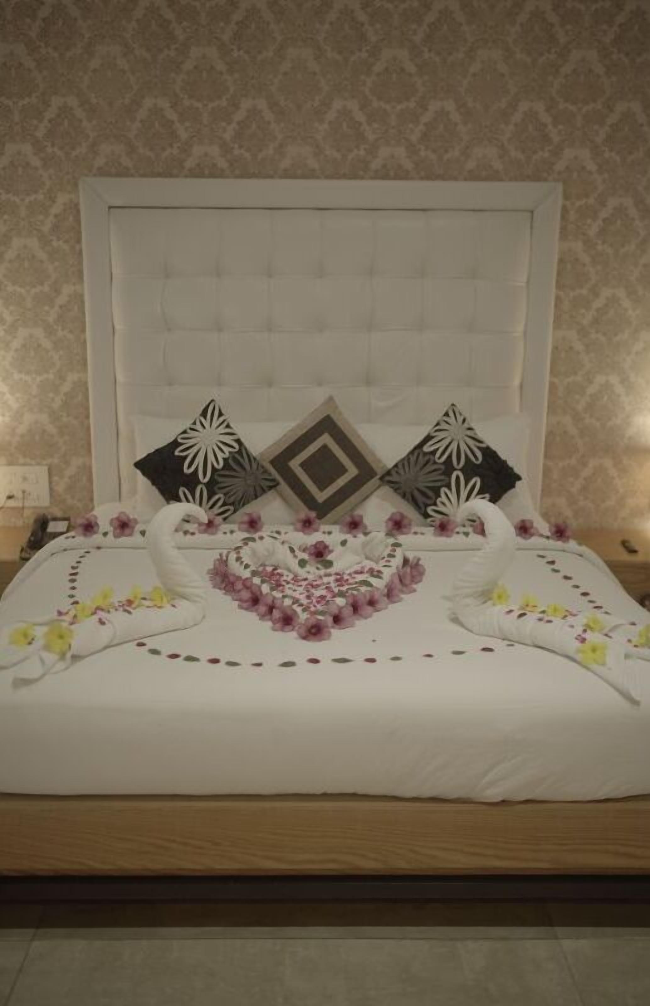 Una cama bien hecha con almohadillas decorativas y una toalla dispuesta en forma de cisne.