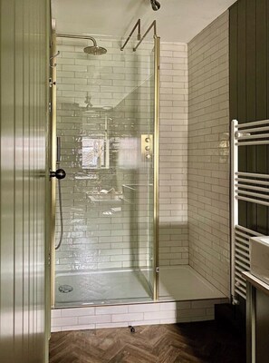 A glass-enclosed shower with a white tiled wall and a wooden floor. - Peverel House, Tideswell. Sleeps 4, Dog Friendly (Buxton)