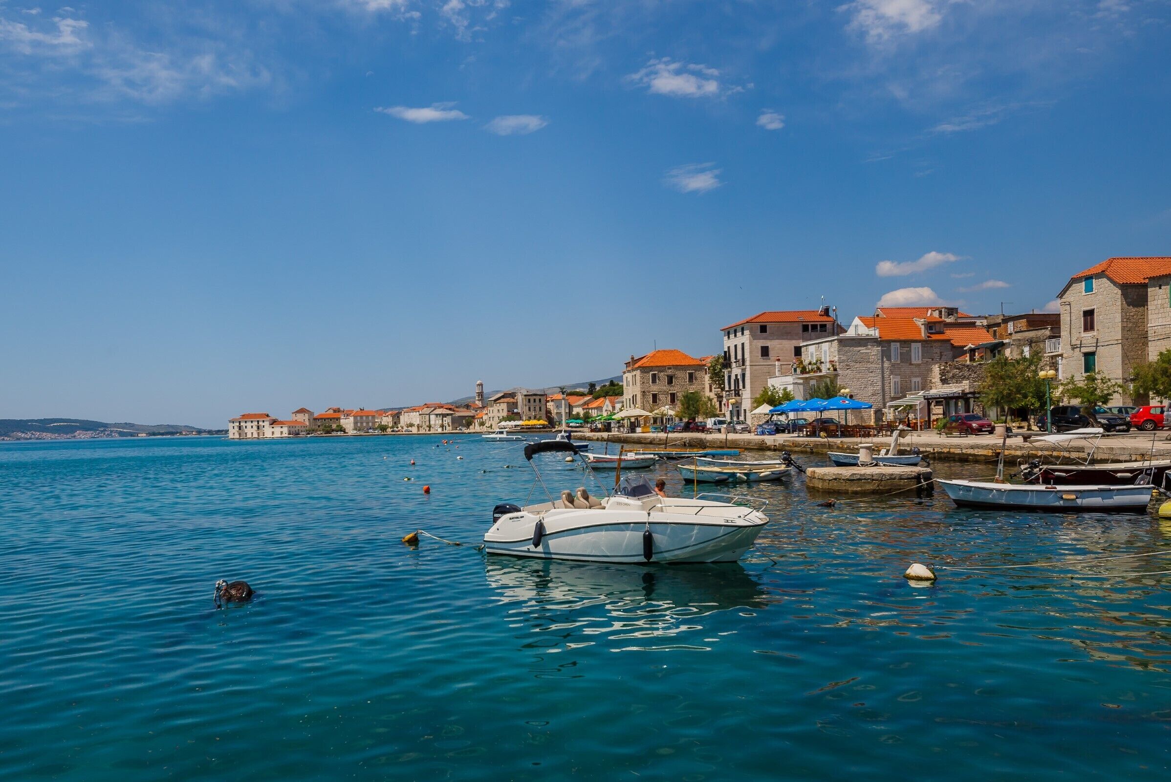 A coastal town with stone buildings, a marina, and boats.