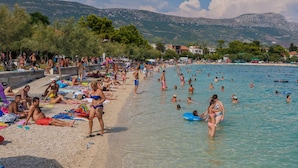 Une plage bondée où les gens se prélassent au soleil et se baignent.