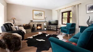 A living room with a fireplace, a television, teal sofas, and a black and white cowhide rug. - WESTWOOD COTTAGE - A spacious farm cottage close to superb East Lothian beaches  (Longniddry)