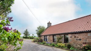 A stone building with a red-tiled roof, a gravel driveway, and surrounding greenery. - WESTWOOD COTTAGE - A spacious farm cottage close to superb East Lothian beaches  (Longniddry)
