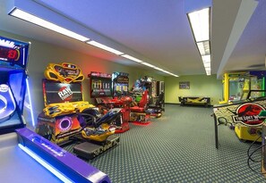 Habitación con juegos de arcade, incluyendo 'Rail Fury' y 'El Mundo Perdido: Jurassic Park'.