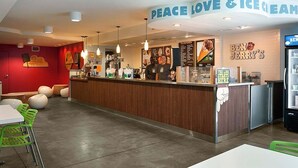 A cafe with a wooden counter, green chairs, and a menu board.